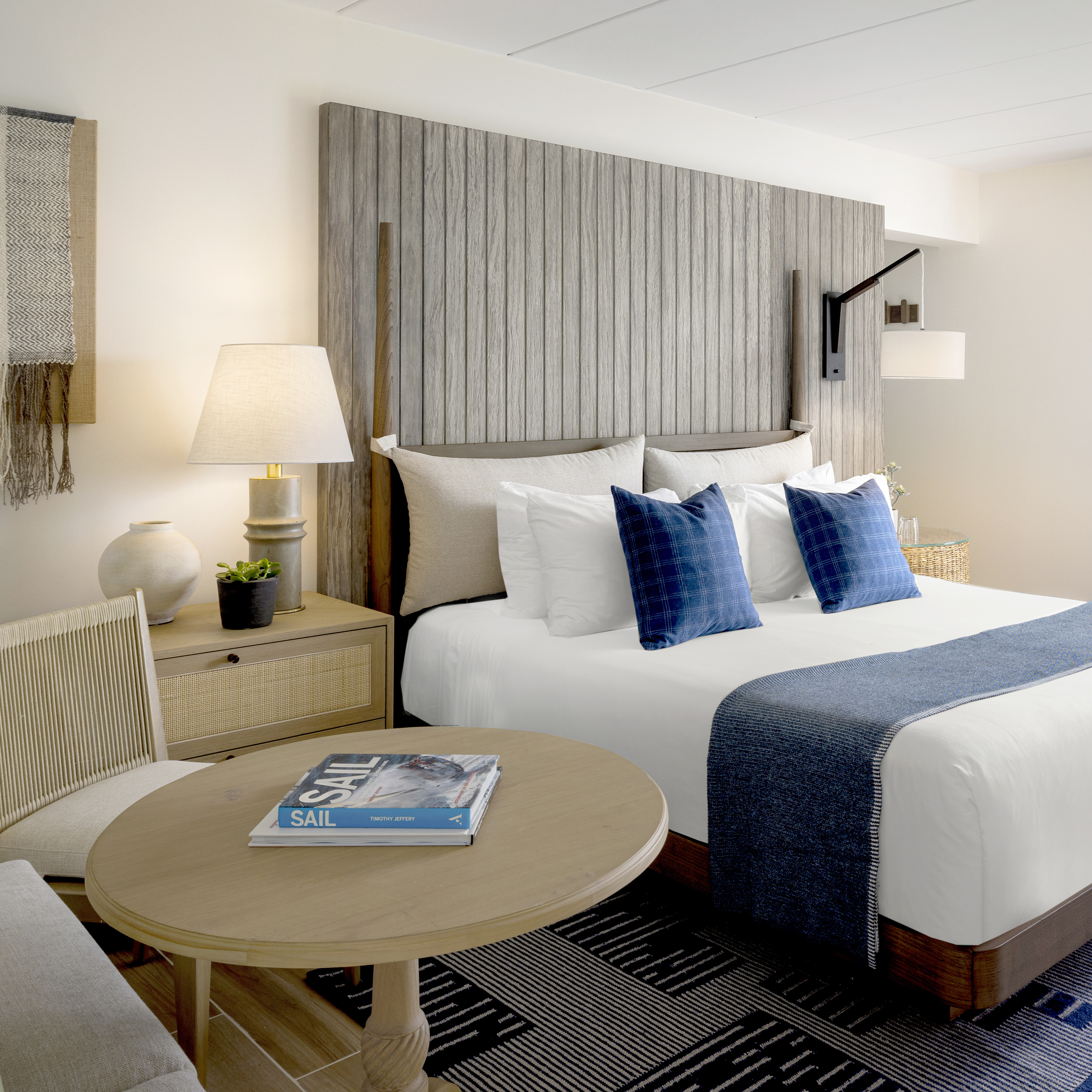 A hotel room with a large bed, a round table, and a chair.