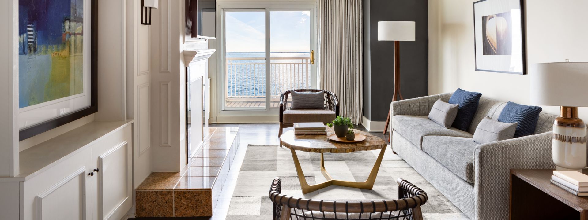 The living area of a modern hotel room with a fireplace and ocean views