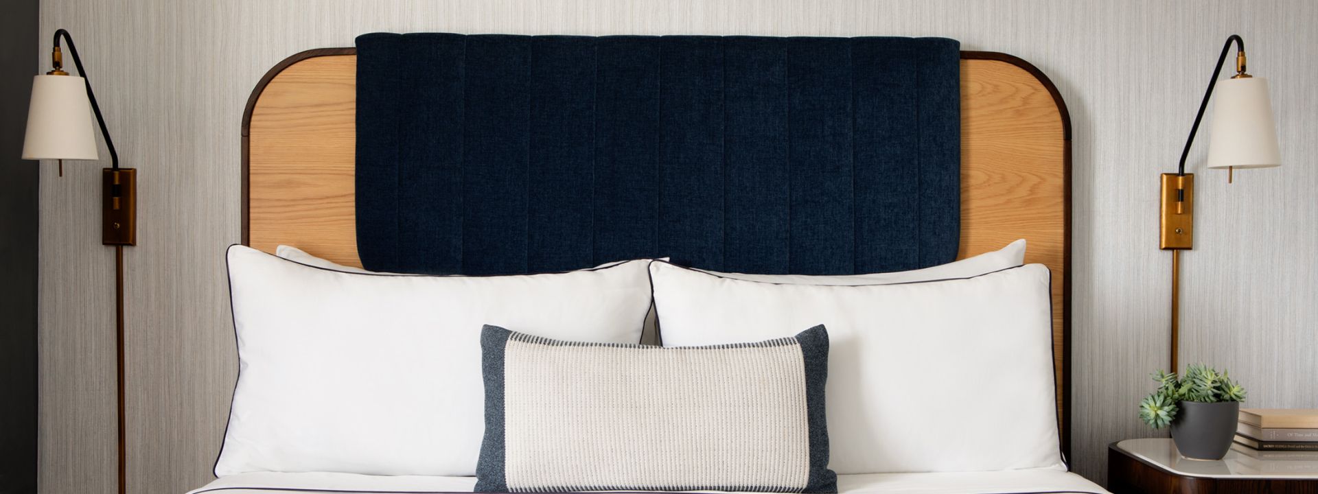 A king bed decorated with pillows in a hotel suite.