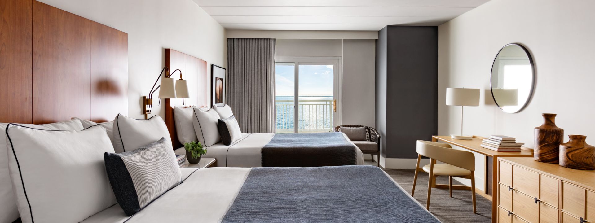 A modern hotel suite with two queen beds and an ocean view.