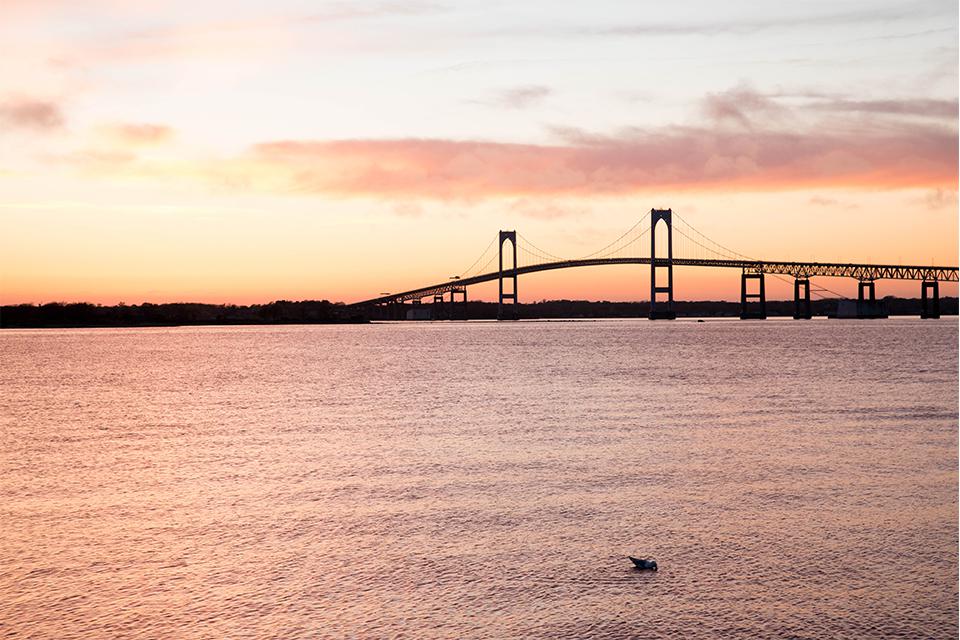 A serene waterfront scene with a bridge at sunset.