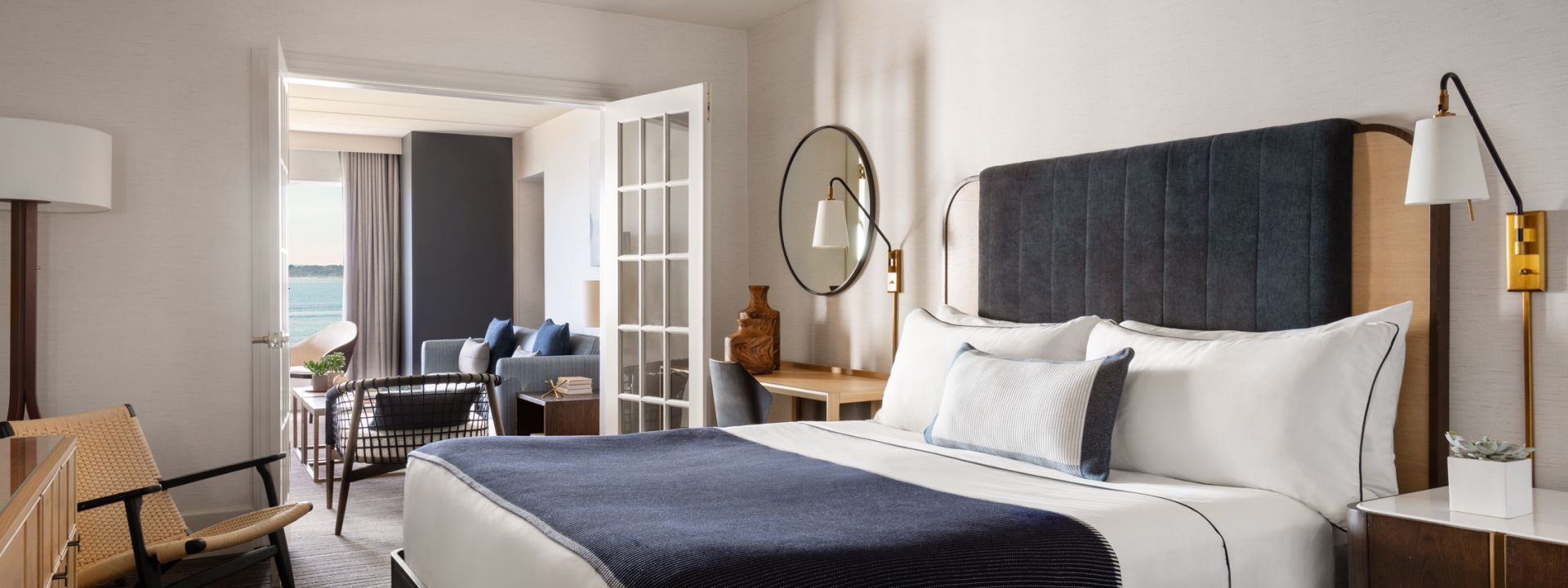 A king bed in a bi-level hotel suite with a balcony and ocean views.