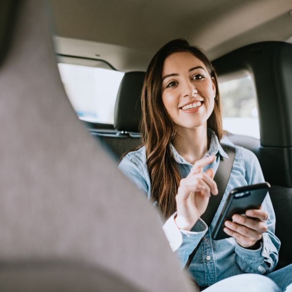 A woman on her phone in the back of a ride share.