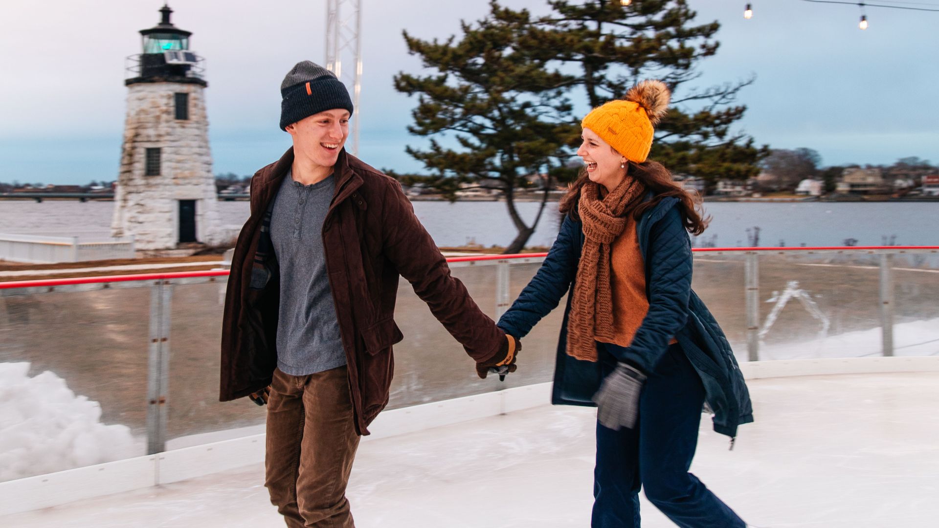 A couple holding hands while ice skating outdoors.