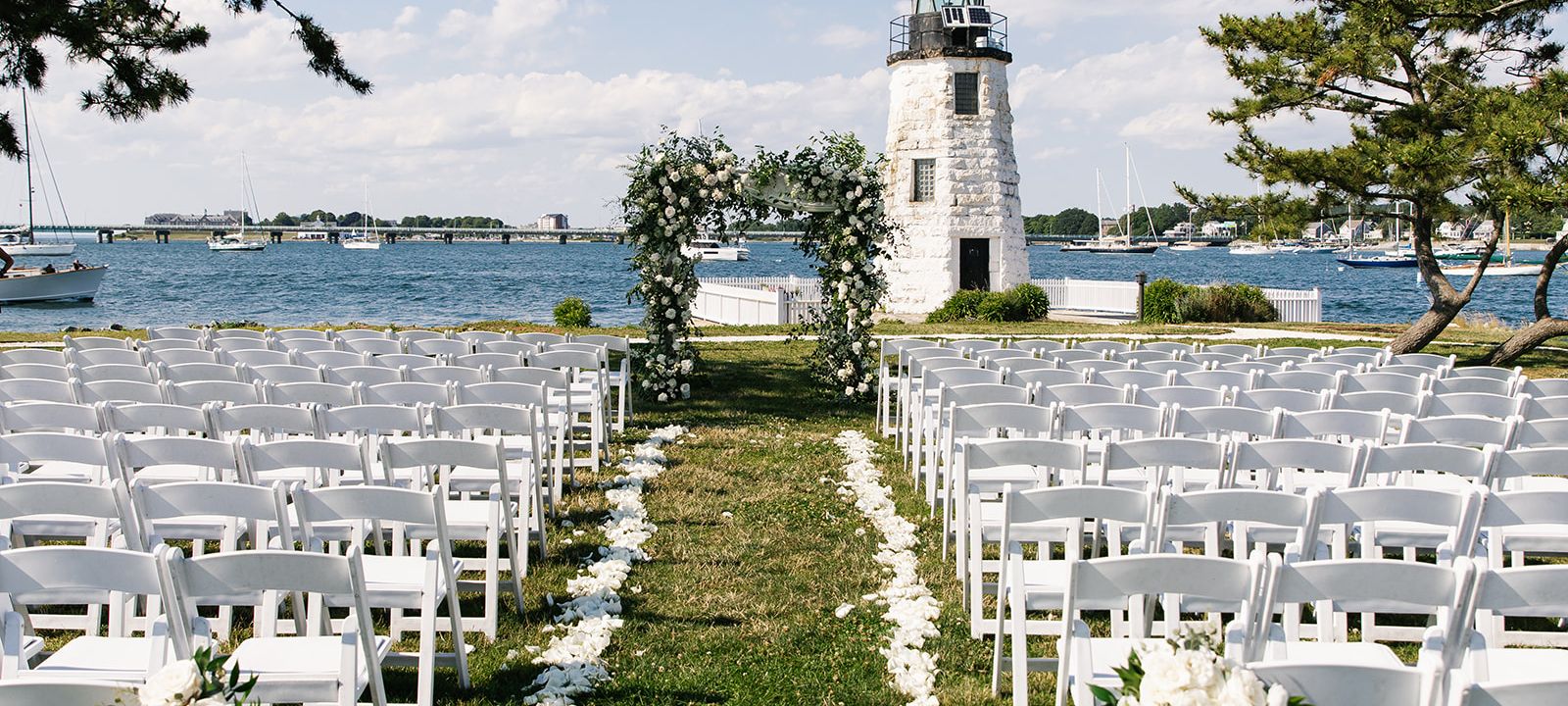 Outdoor seating for a seaside wedding near a lighthouse.