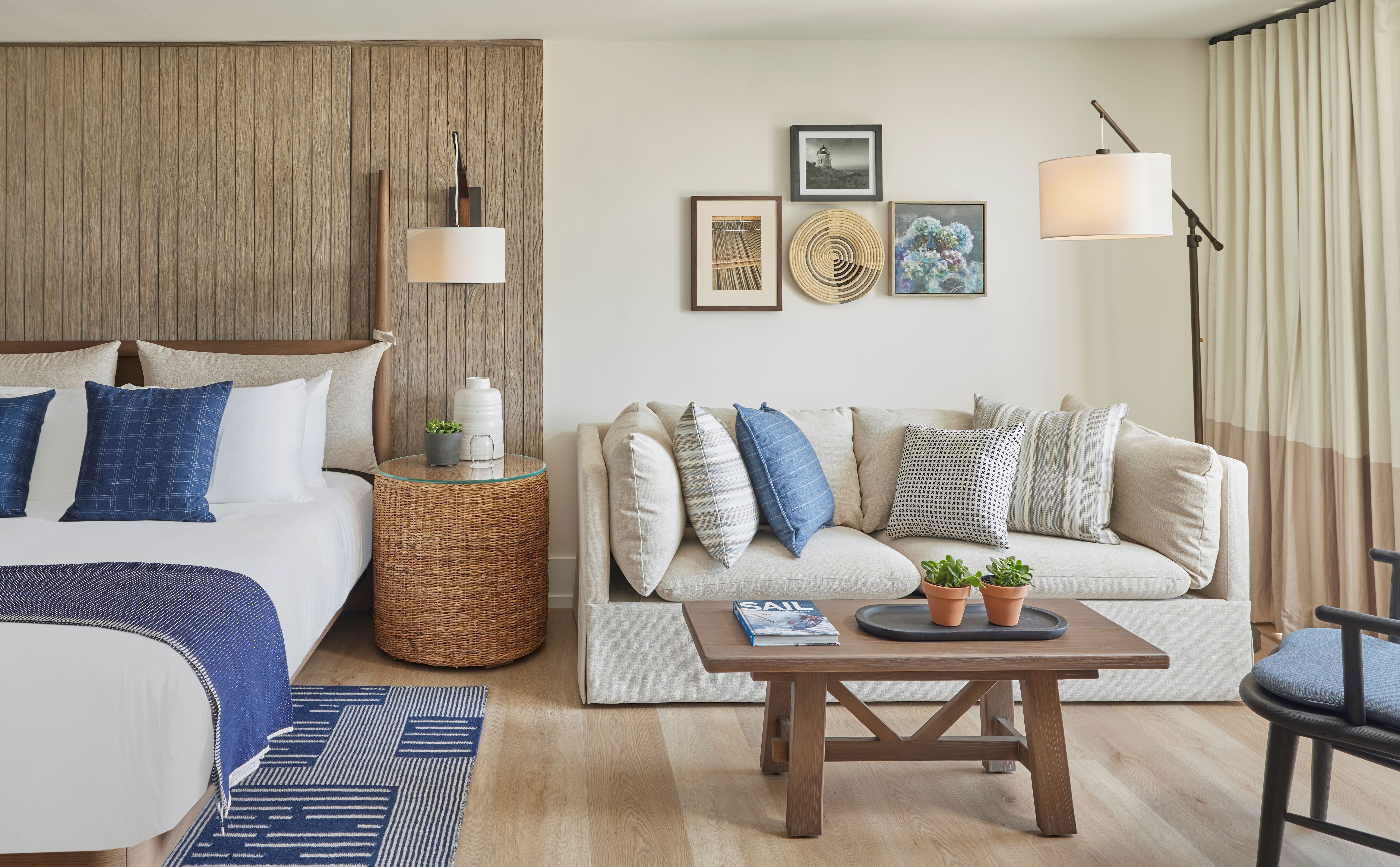 A wide view of a hotel room with a sofa, coffee table, and bed.