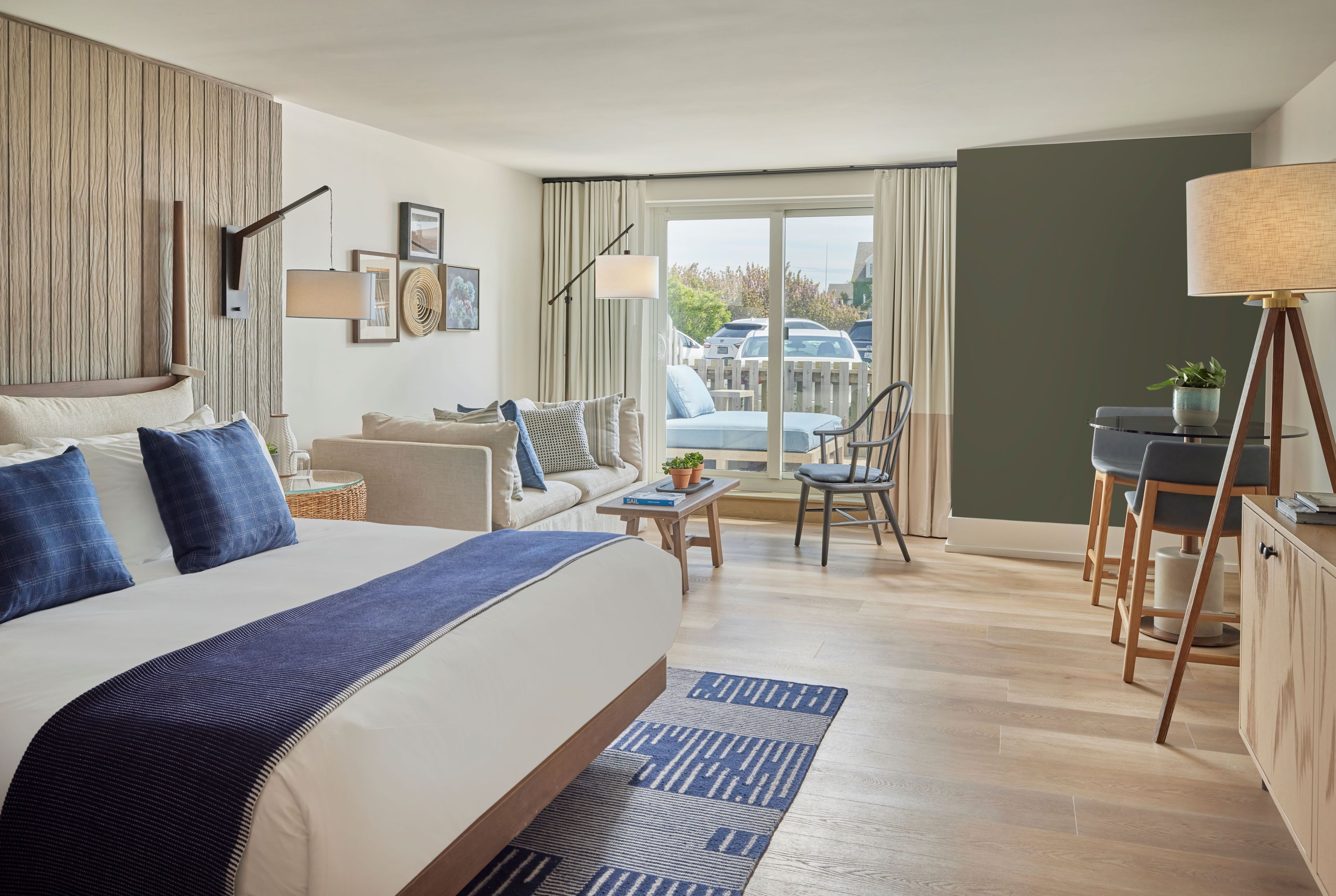 A wide view of a hotel room with a king-sized bed, sitting area, and sliding glass doors leading to a balcony.