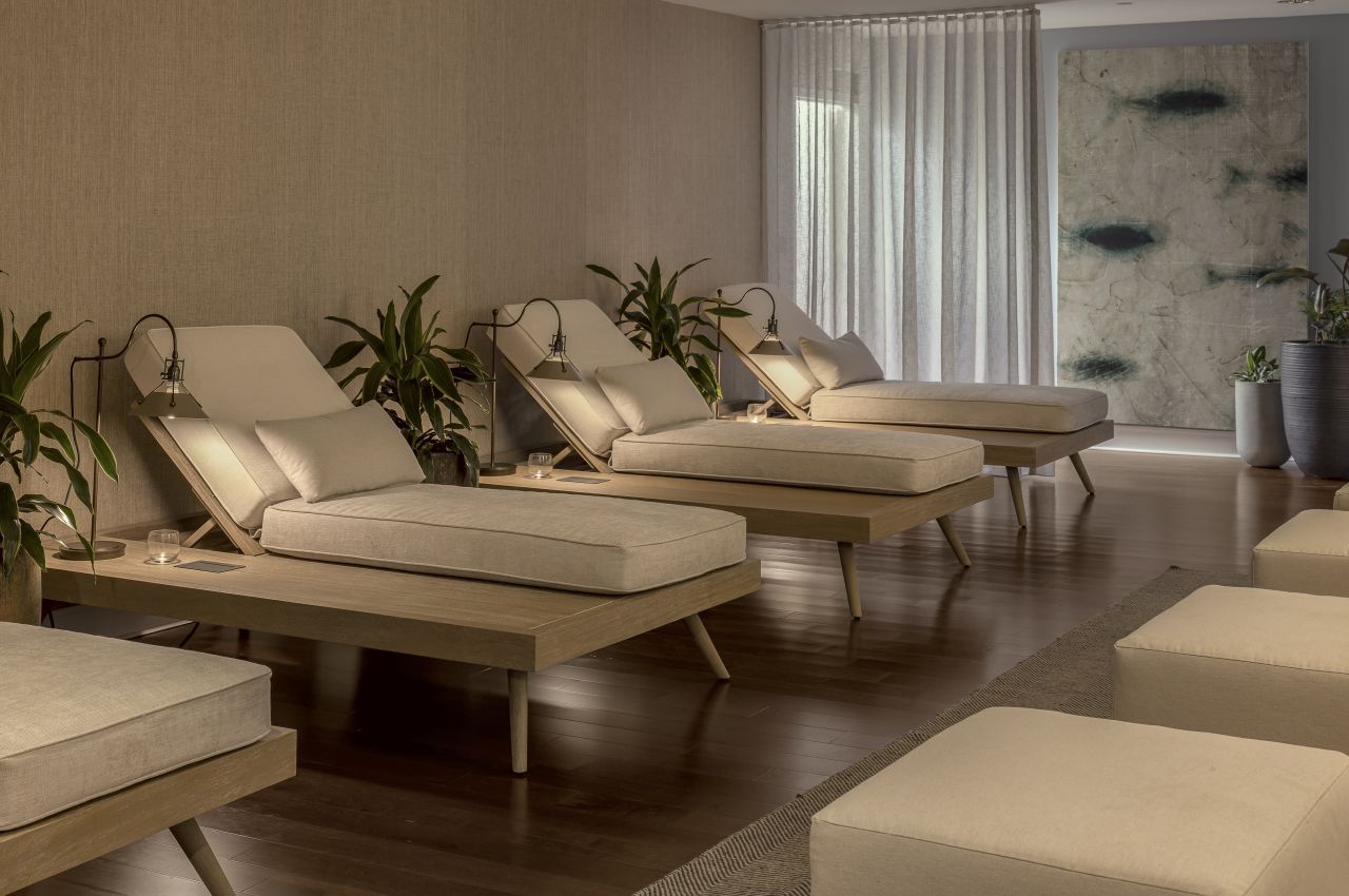 A serene spa relaxation area with reclining chairs, plants, and artwork.