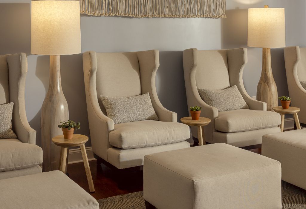 A serene spa setting with wingback chairs, wooden side tables, and lamps.