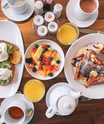 A breakfast spread with toast, fruit, and drinks on a wooden table.