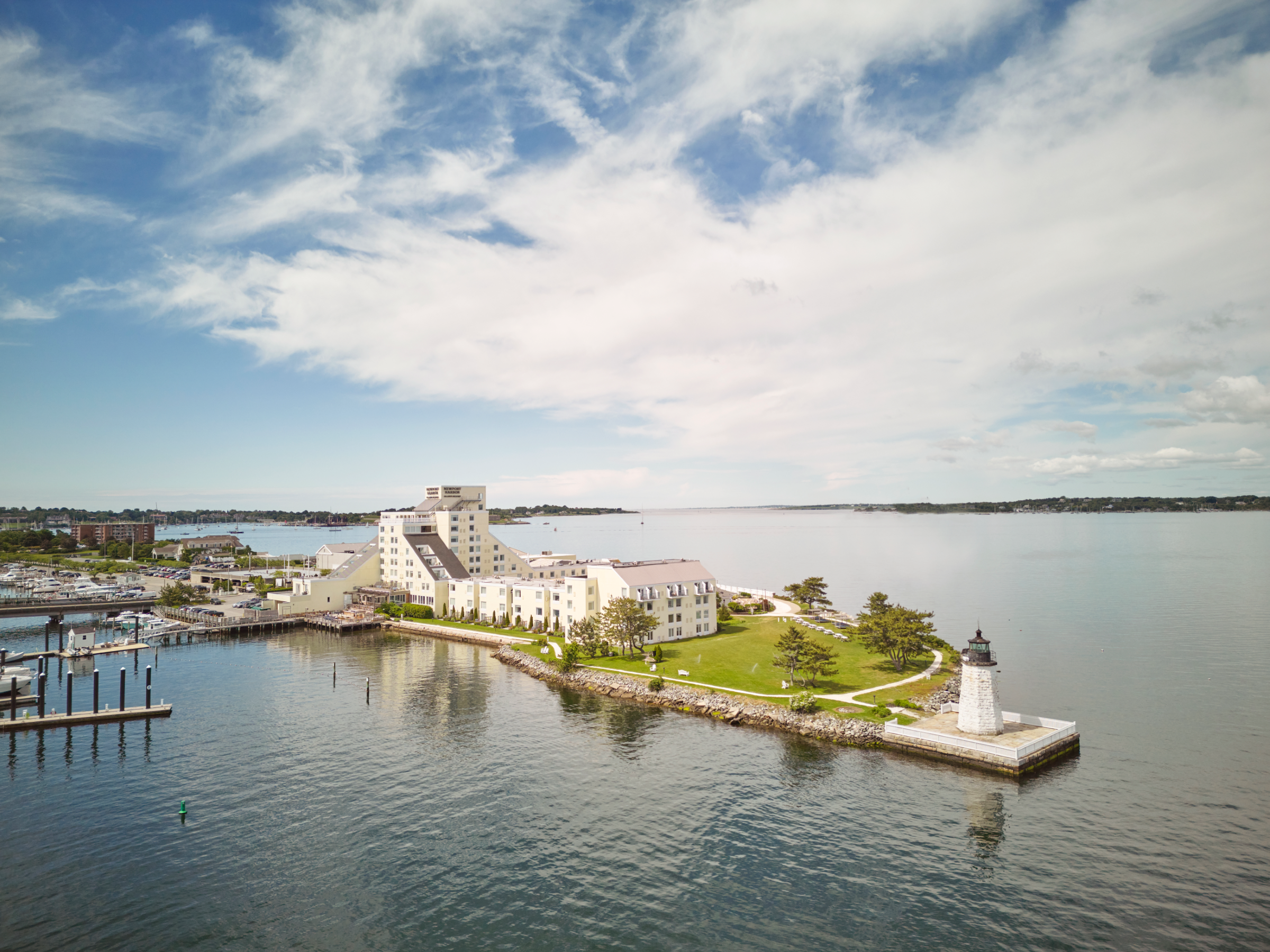 An aerial view of a hotel on a waterfront property with a lighthouse.