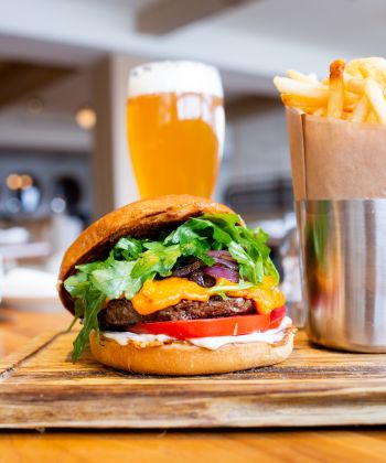 A burger, fries, and a beer on a table.
