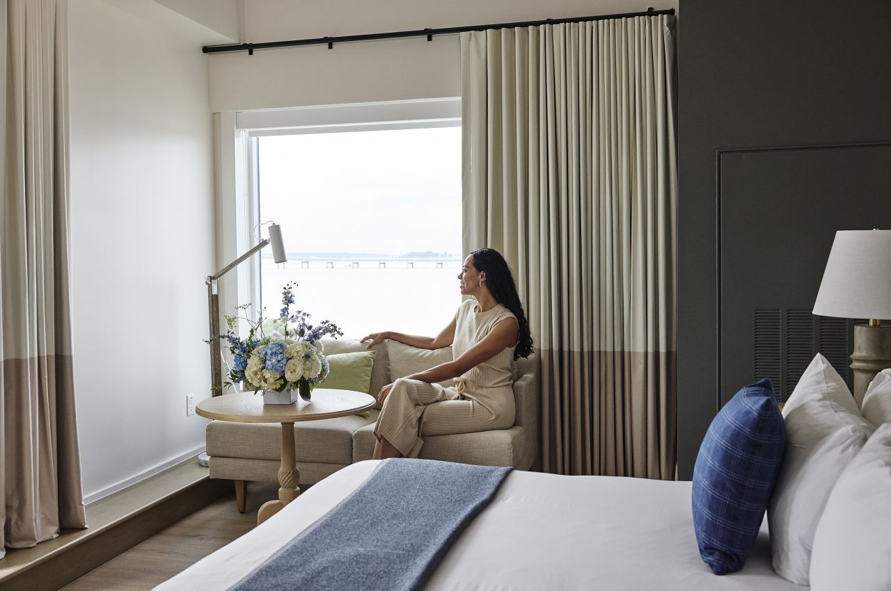 A hotel room with a bed, sofa, table, and flowers